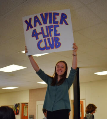 XHS Student holding Xavier 4-Life Club Sign
