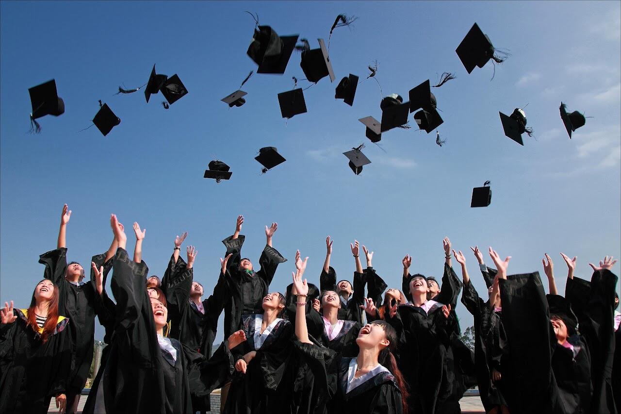 graduates tossing their caps into a blue sky