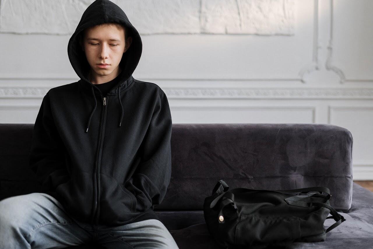 teen boy in a black hoodie looking troubled